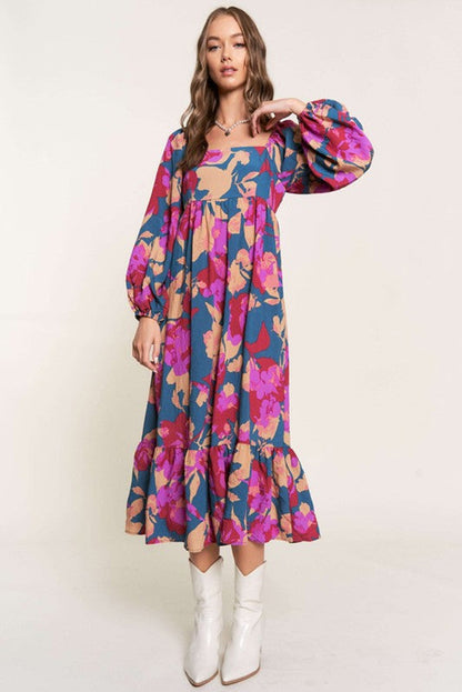 Woman wearing a colorful floral dress with white boots on a plain background